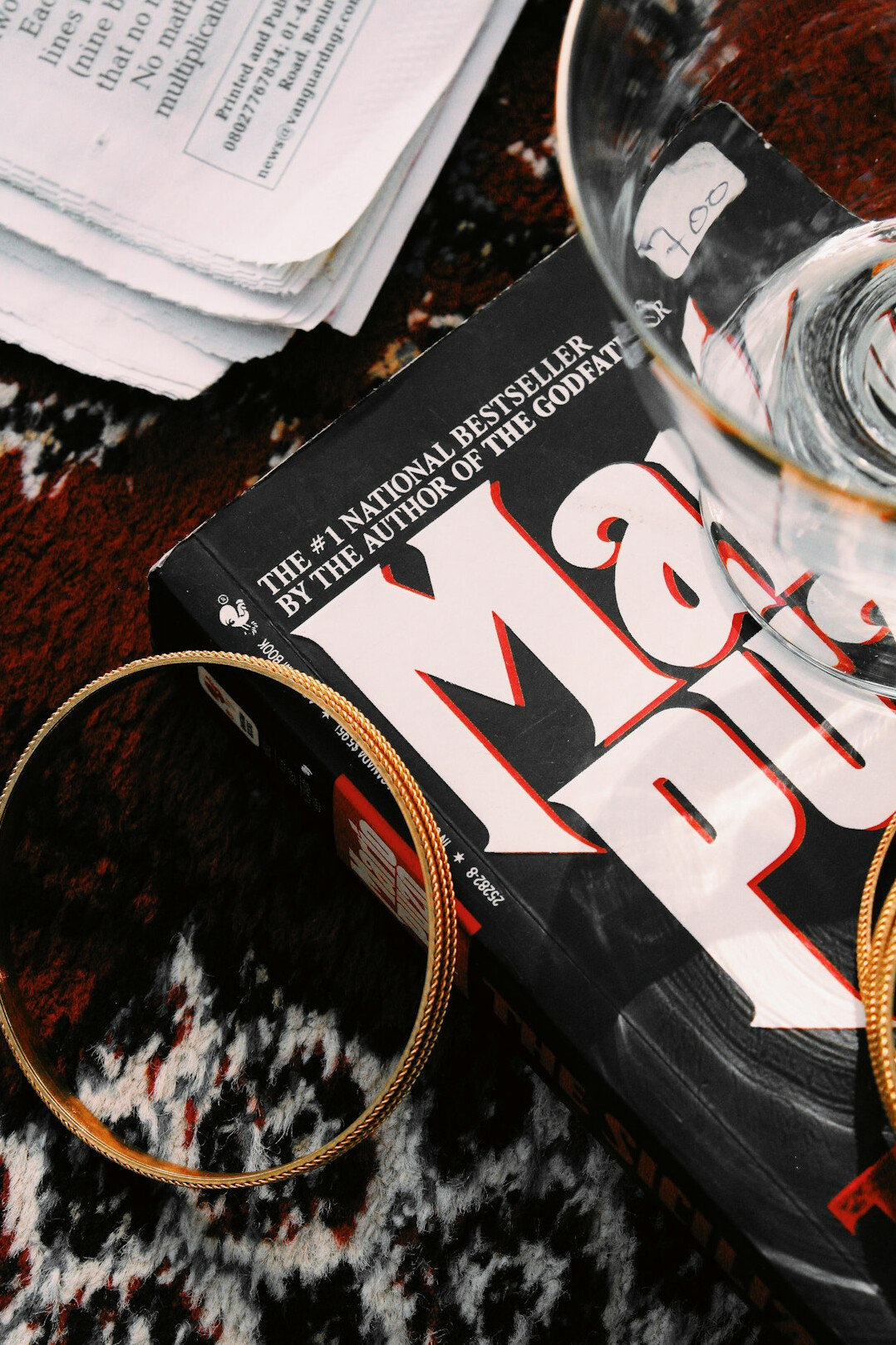 Stack of classic crime novels with a magnifying glass